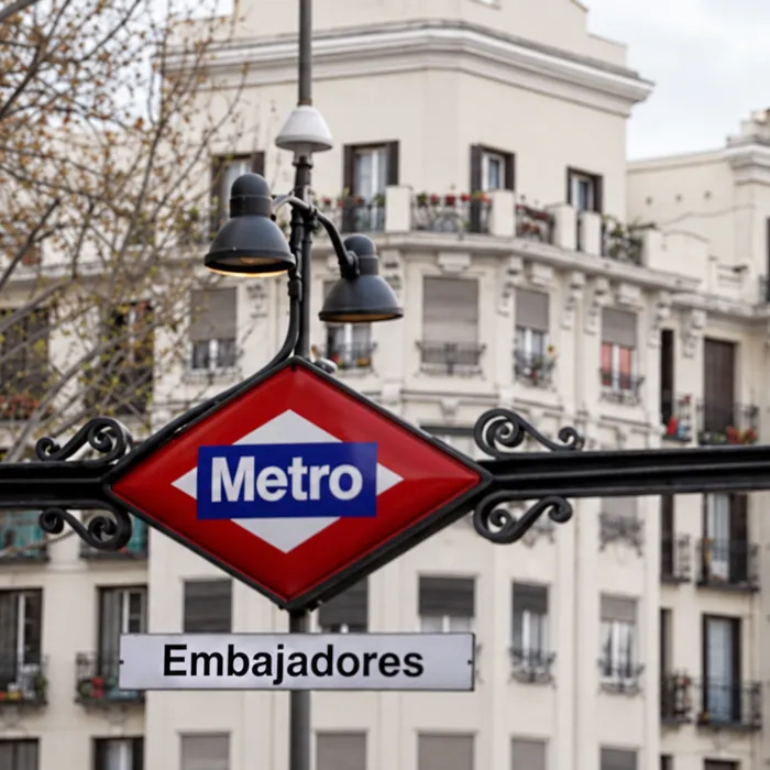 Cartel de metro Embajadores delante de edificios antiguos del barrio, con bombín nuevo y llaves